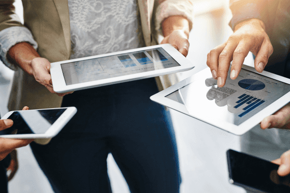 Three people gathered in a circle looking at tablets