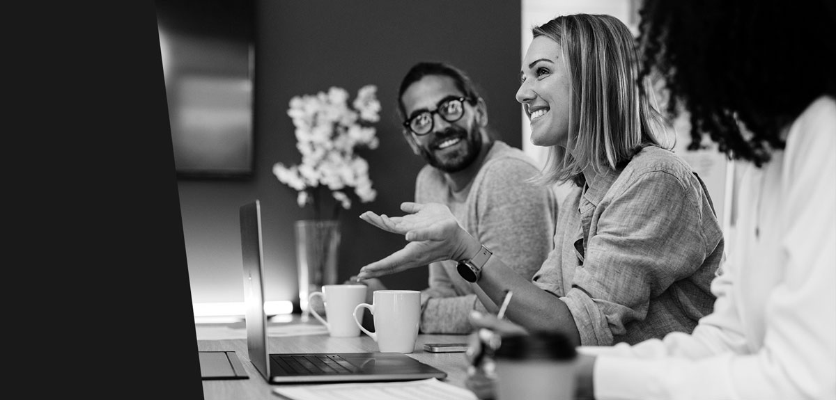 a pair of employees sit in conference room and smile as they hold a meeting